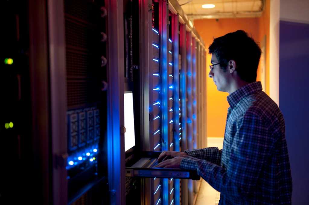 man in network room data center tech troubleshooting